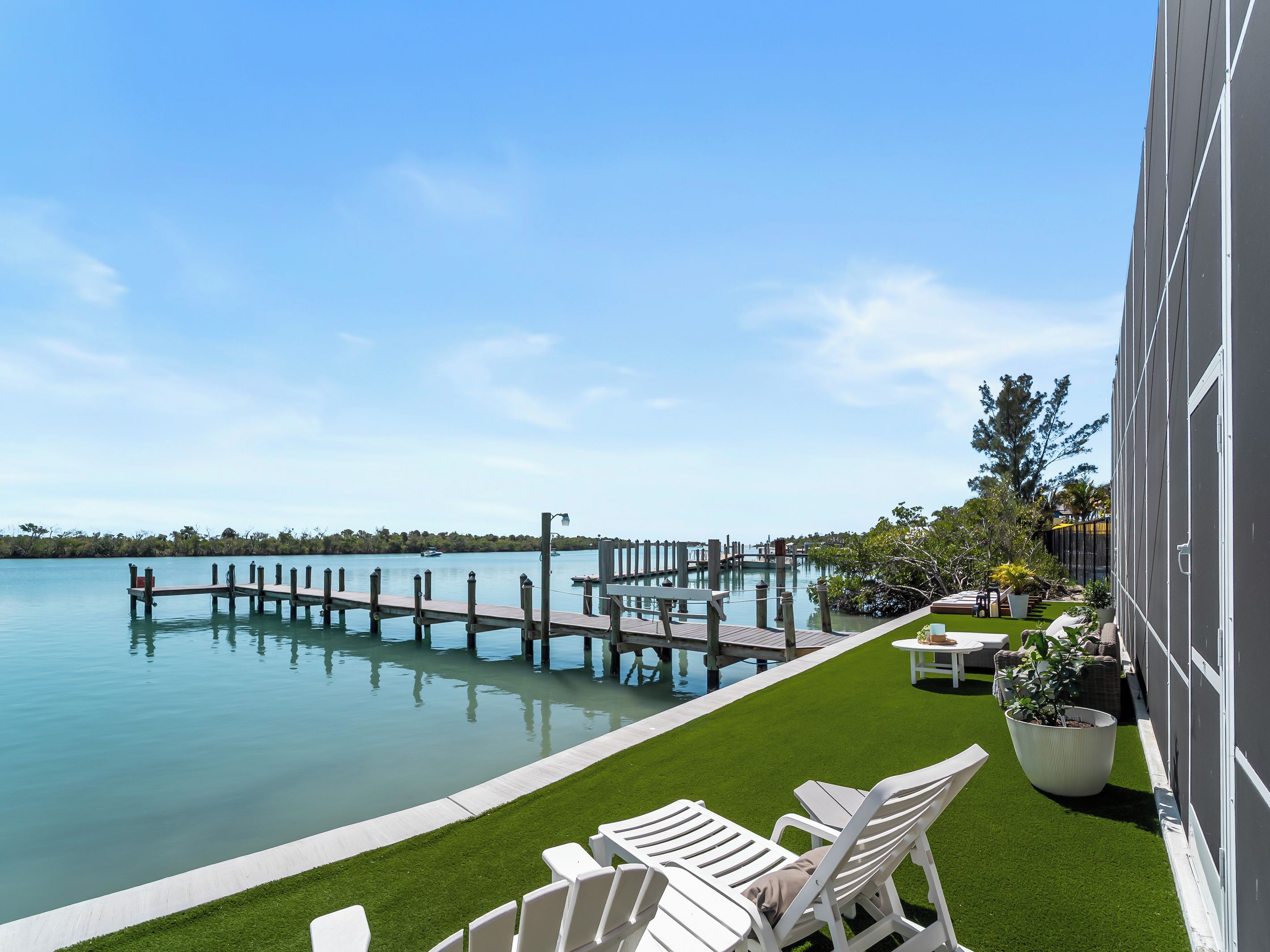 Eine Poolterrasse am Wasser mit Liegestühlen und einem kleinen Tisch mit Stühlen.