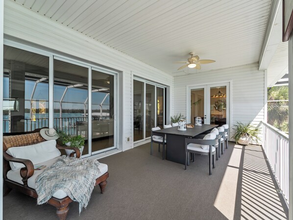 A covered outdoor area with a dining table, chairs, and a sofa.