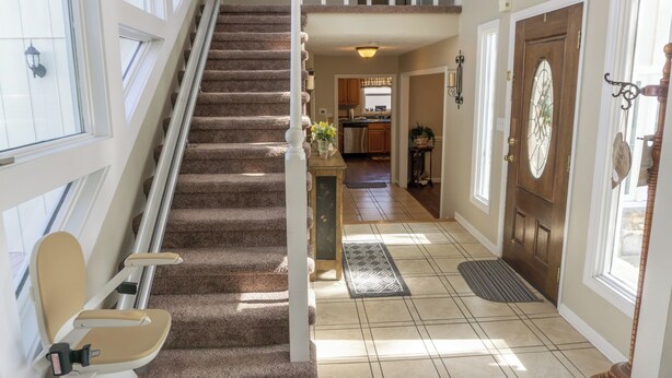 Un escalier menant à un deuxième étage, un coin cuisine et une porte ornée d’un panneau de verre décoratif.