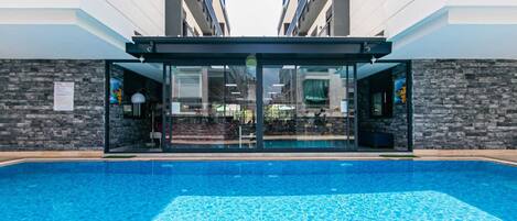 Una piscina al aire libre, sombrillas, sillones reclinables de piscina