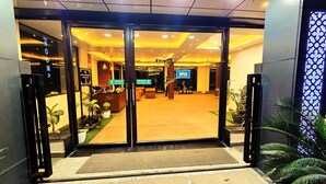 Een hotel lobby met een receptiebalie, een bordje met de tekst 'Slide to Open' en een bordje met de tekst 'We Are Open'.