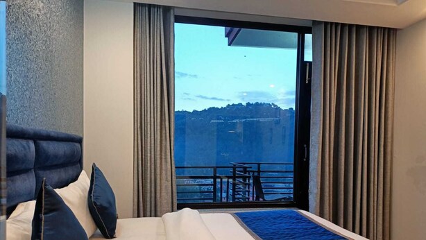 Een hotelkamer met een bed, uitzicht op een balkon en gordijnen.