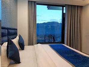 A hotel room with a bed, a view of a balcony, and curtains. -  Barog Residency (Solan)