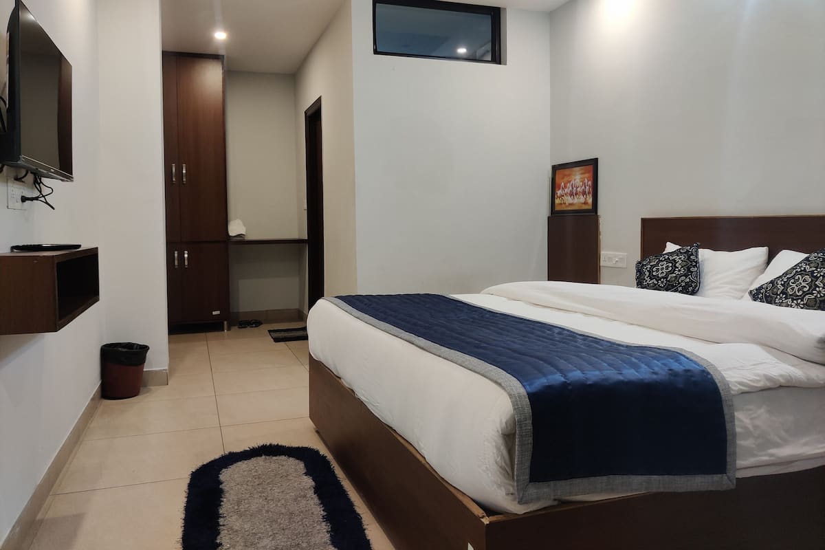 Un dormitorio con una cama, televisión montada en la pared, una puerta y una ventana.