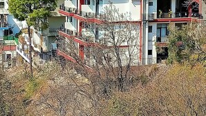 Een meerlaags hotel met balkons en een groen dak.