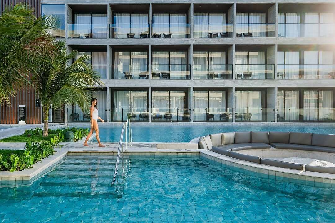 A modern hotel with a pool area, including a lounge with seating and a poolside bar.