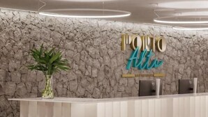A reception desk with a stone wall backdrop and a sign that reads "PORTO Alto." - Porto alto resort  (Ipojuca)