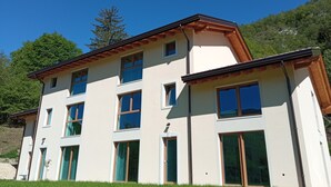 A multi-story building with large windows and a sloped roof. - Ai Monti (Barcis)