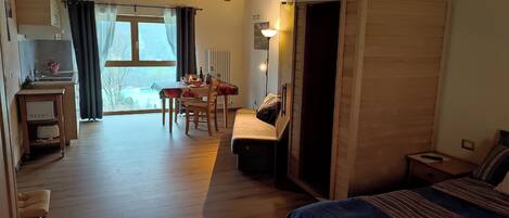 Una habitación acogedora con cama, escritorio, zona de comedor y vista a un lago.
