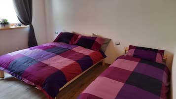 Une chambre avec deux lits en bois, chacun recouvert d’une courtepointe aux couleurs violettes et roses.
