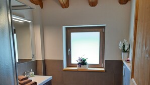 A bathroom with a wooden ceiling, a window with a view, a sink, a toilet, and a mirror. - Ai Monti (Barcis)