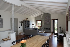 A spacious living area with a wooden dining table, grey sofa, and a fireplace.