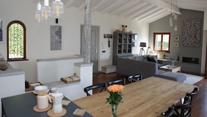 A spacious living area with a wooden dining table, grey sofa, and a fireplace.