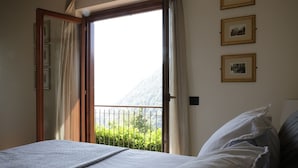 A bedroom with a bed, a window with curtains, and framed pictures on the wall.