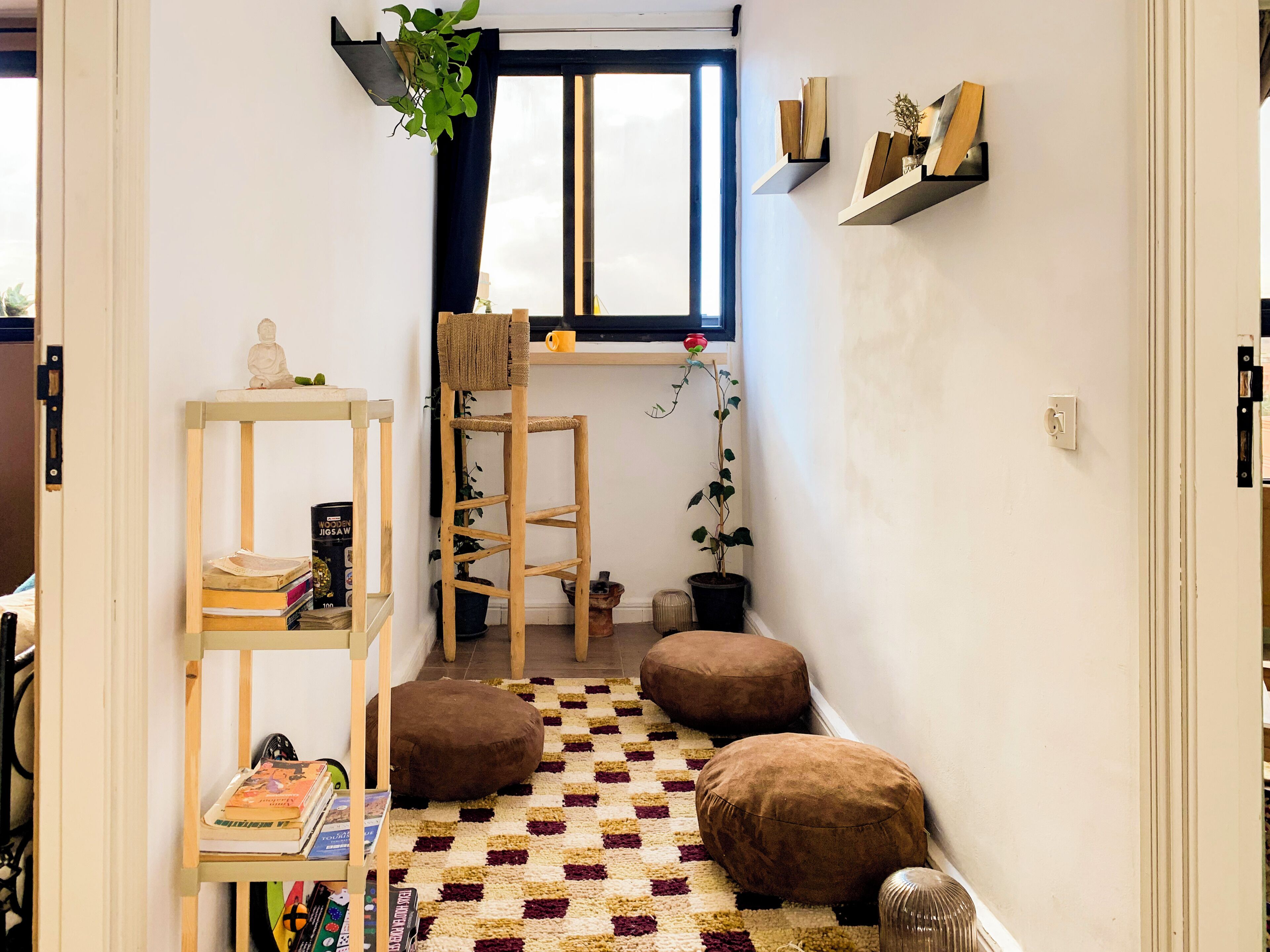 Una habitació acollidora amb un terra de petxines, un arbre rascador per a gat, una prestatgeria i una finestra amb vistes.