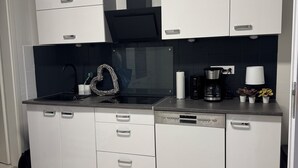 Una cocina moderna con armarios blancos, una estufa negra y un lavavajillas Siemens.