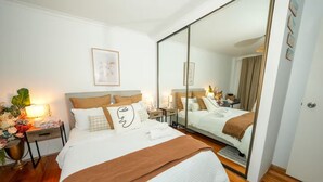 A modern hotel room with a large bed, a bedside table with a lamp, a mirror, and a view of the hallway. - 5 minutes to the beach!  (Brighton-Le-Sands)