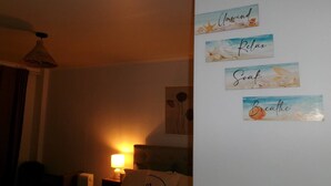 A bedroom with a bed, a nightstand, a lamp, and wall art with motivational phrases. - 5 minutes to the beach!  (Brighton-Le-Sands)