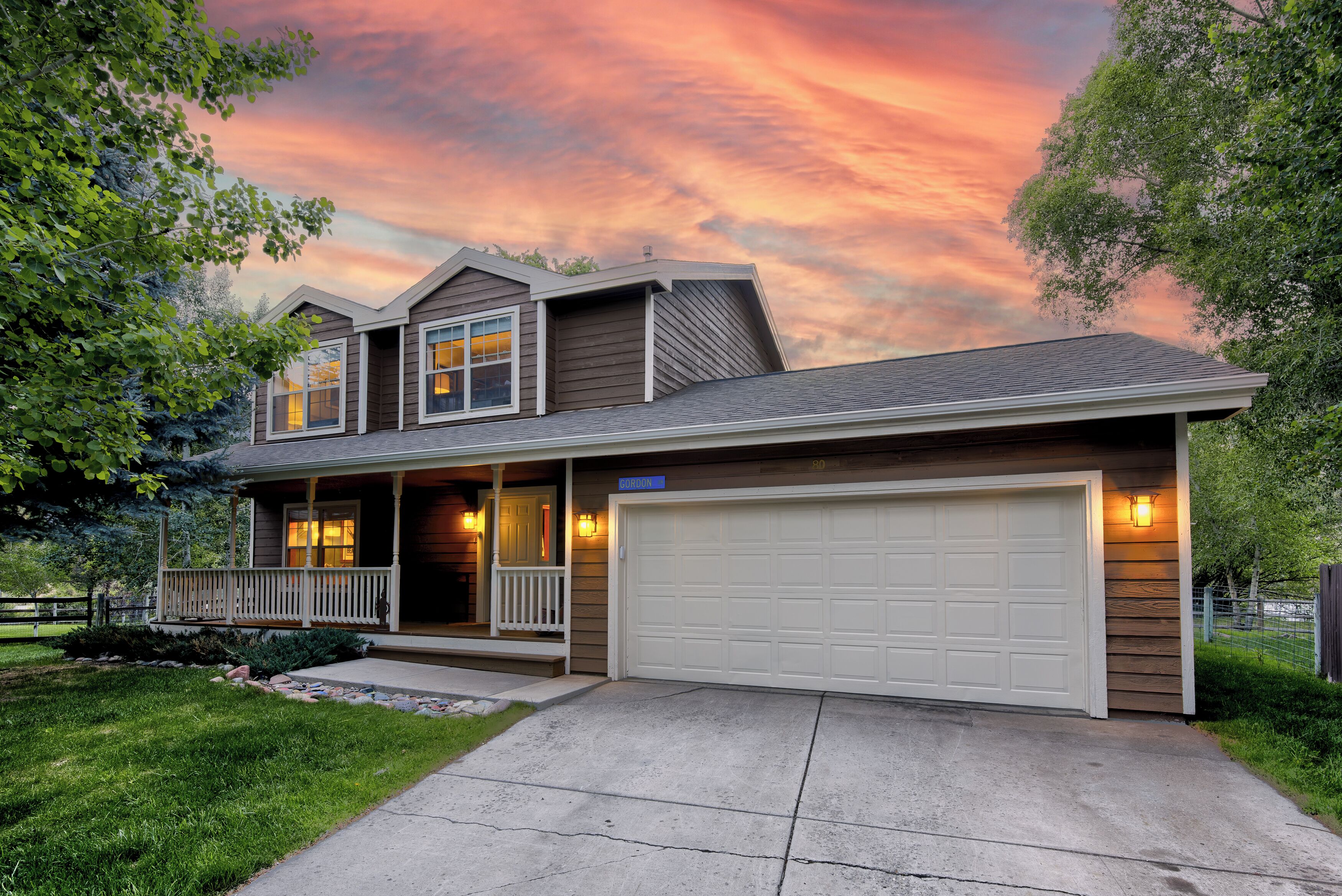 A two-story house with a covered porch, a garage, and a well-maintained lawn.