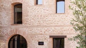A building with a stone facade, a sign reading "ALMAZARA RESTAURANT," and an arched entrance. - Tradere Hotel Boutique (Moncada)