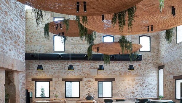 A spacious cafe with rustic stone walls, wooden tables and chairs, and hanging plants. - Tradere Hotel Boutique (Moncada)