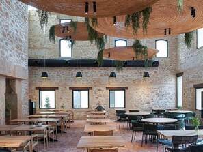 A spacious cafe with rustic stone walls, wooden tables and chairs, and hanging plants. - Tradere Hotel Boutique (Moncada)