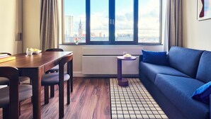 Une chambre moderne comprenant une table à manger, des chaises, un canapé et une grande fenêtre donnant sur la ville.
