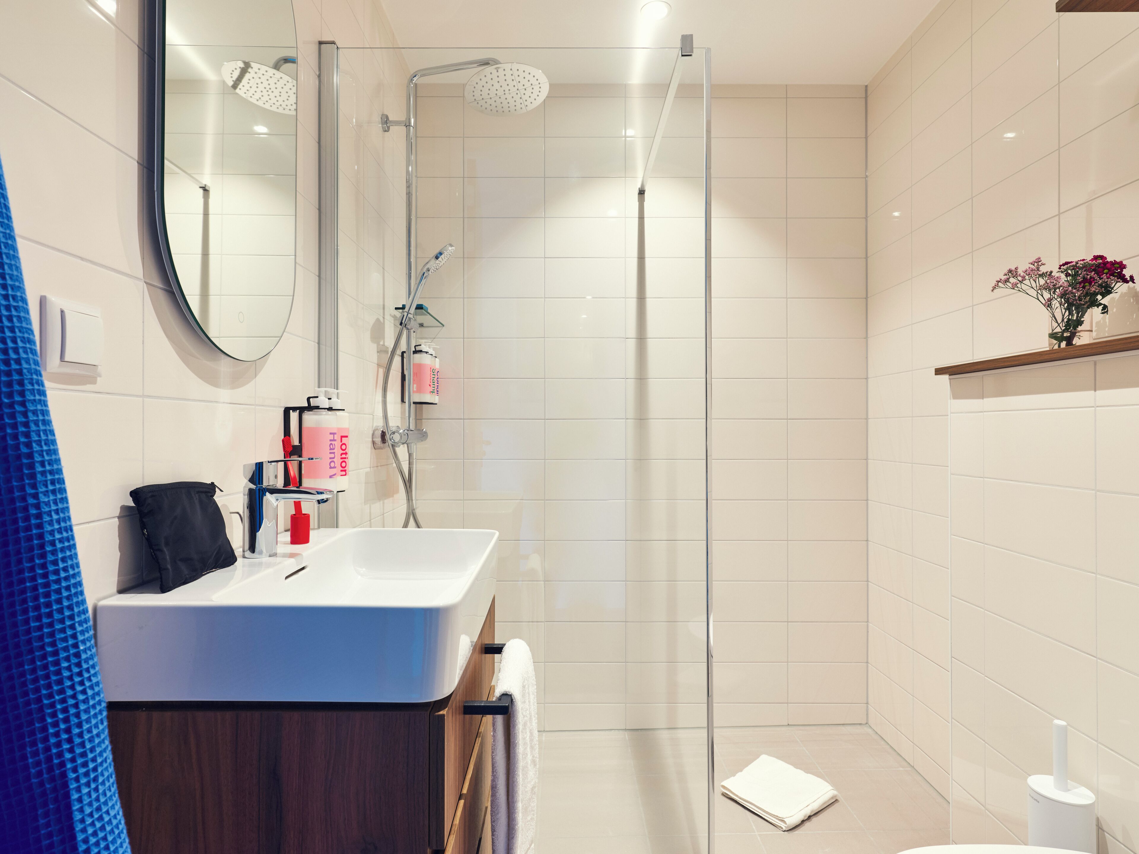 A modern bathroom with a glass shower enclosure, a white sink, and a mirror.
