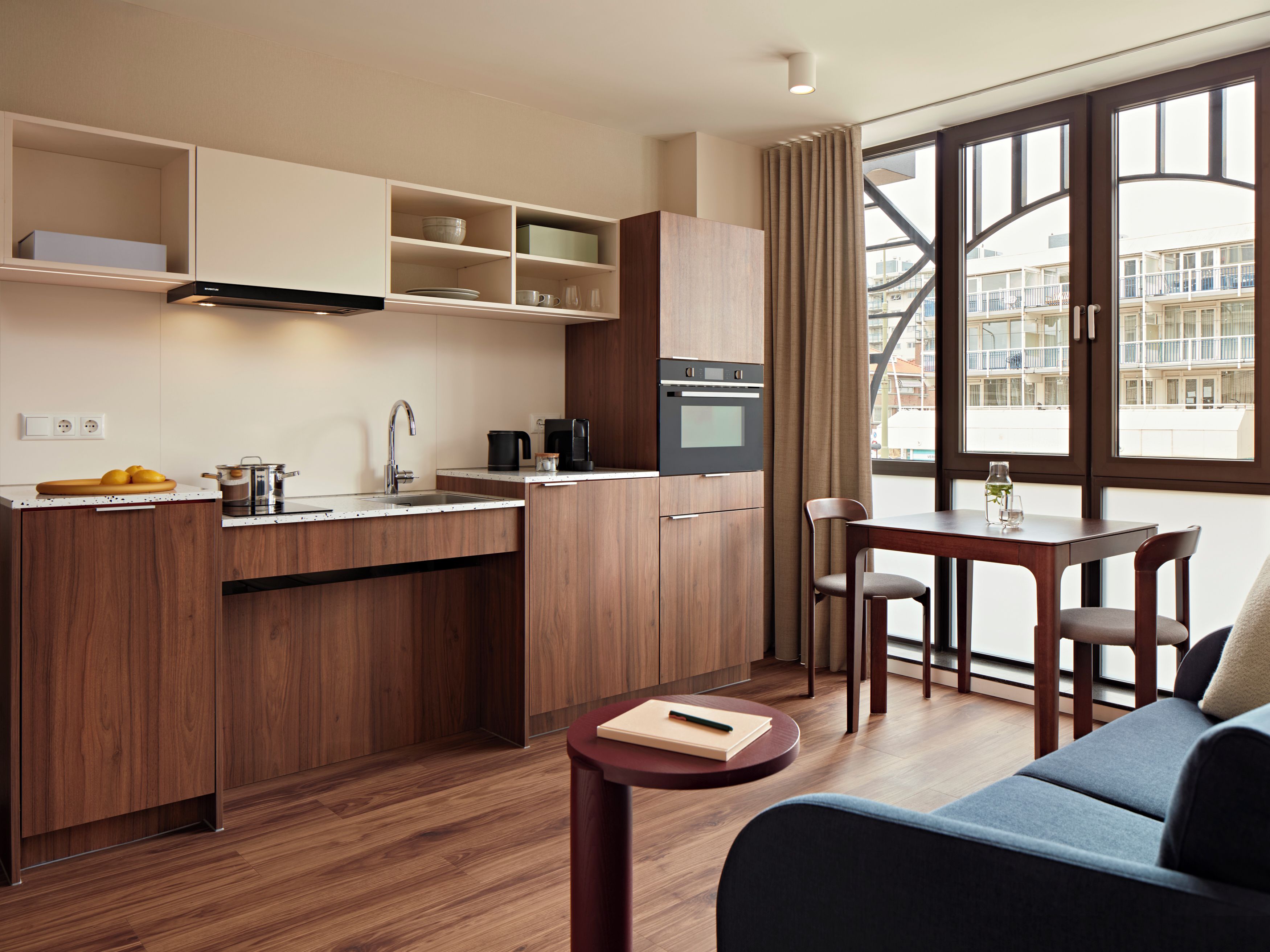 Eine moderne Küche mit Holzausstattung, einem Einbauofen und einem Essbereich mit Tisch und Stühlen.