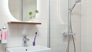 Un baño moderno con un lavabo blanco, un espejo, una ducha y un armario de madera.