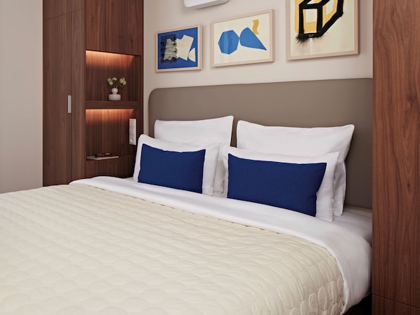 Una cama bien hecha con ropa de cama blanca y azul, un armario de madera y arte abstracto en la pared.