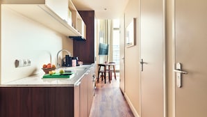 Une cuisine moderne avec un plan de travail en bois, un coin repas avec une table et des chaises, et une vue sur la ville par une fenêtre.