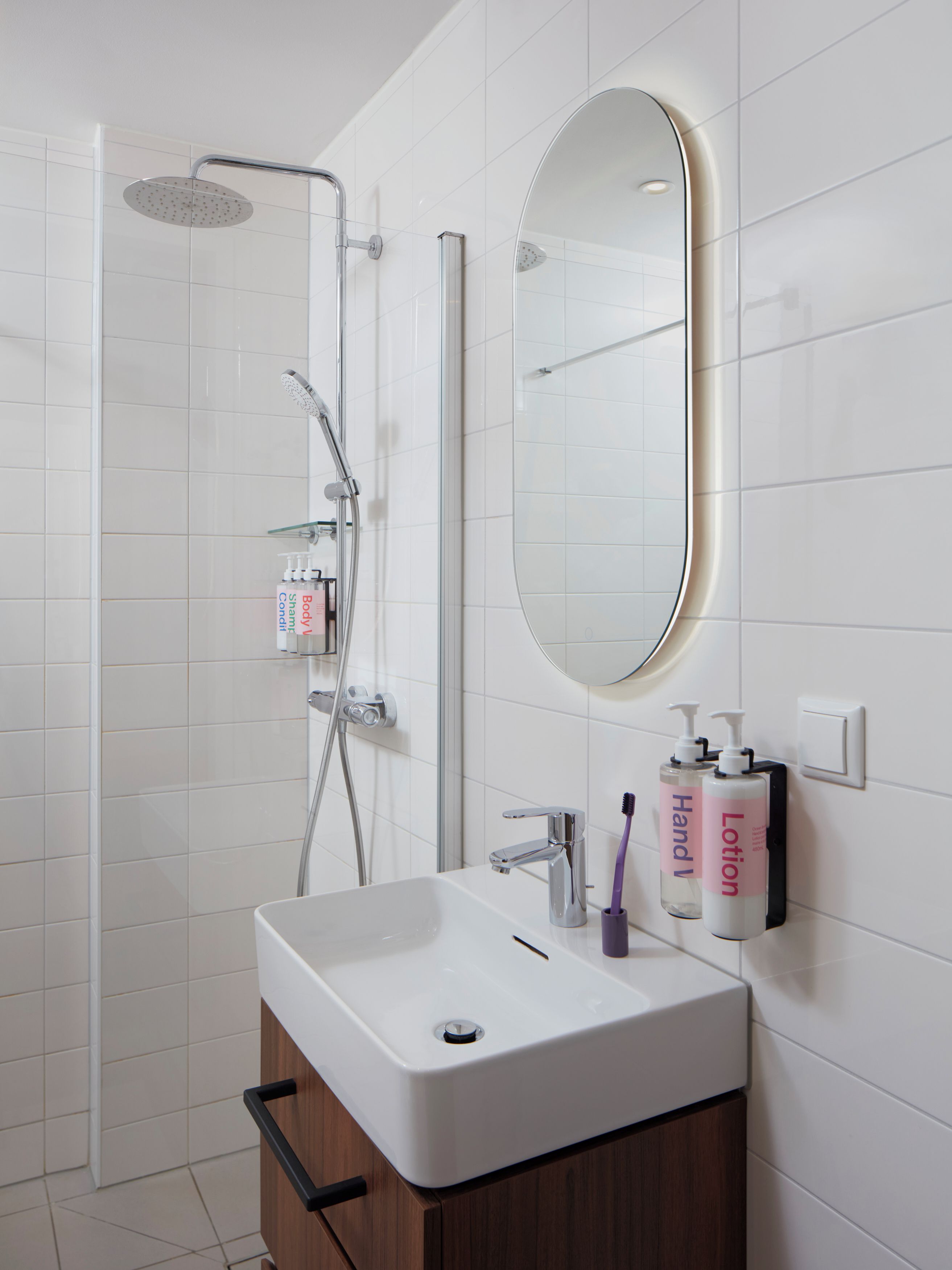 A modern bathroom with a white sink, a mirror, and toiletries.