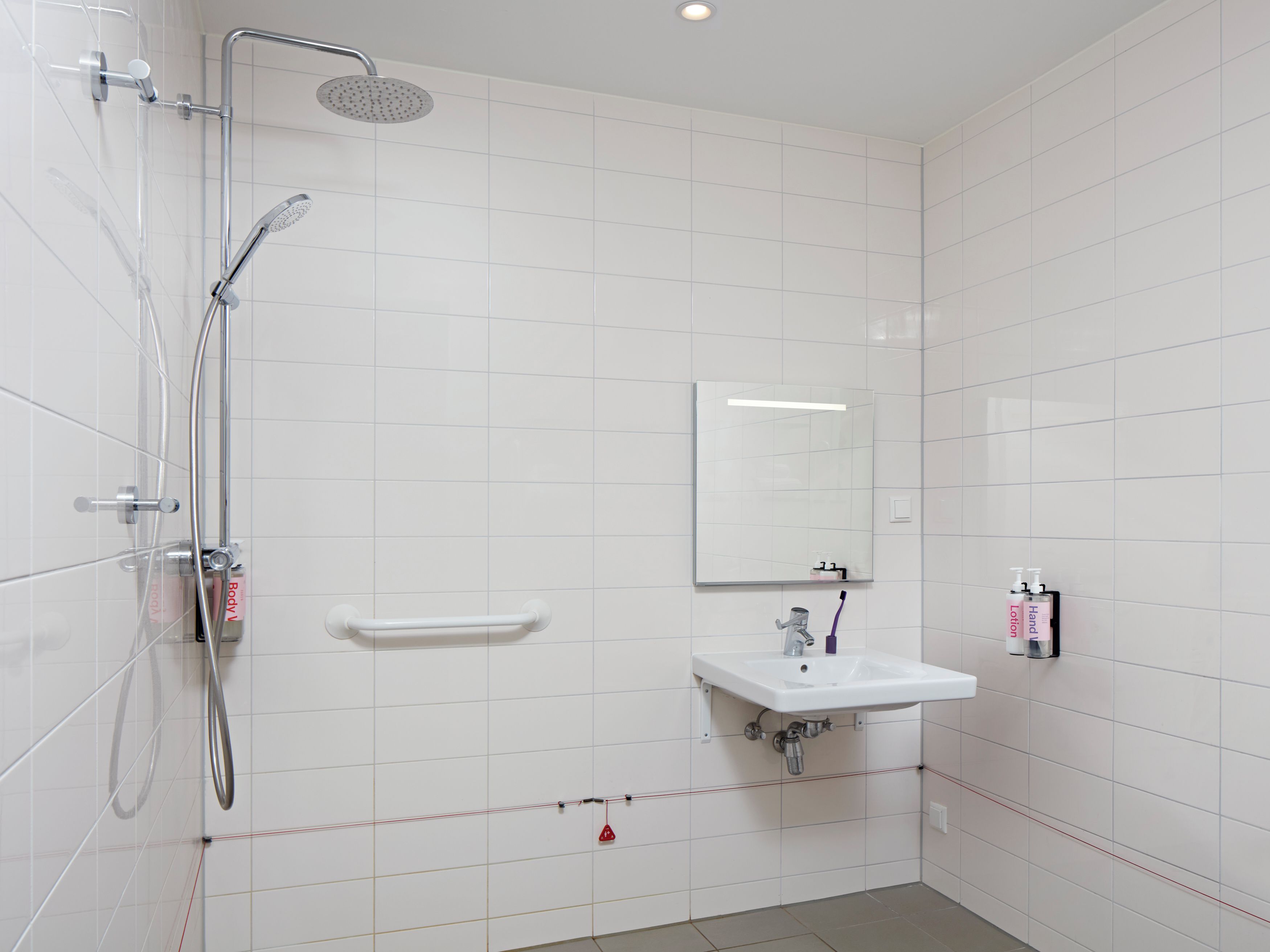 Un baño moderno con ducha, lavamanos y espejo.