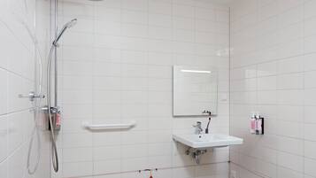 Un baño moderno con ducha, lavamanos y espejo.