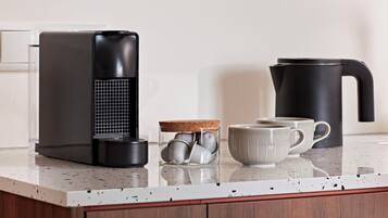 A kitchen counter with a coffee maker, a kettle, a mug, and a glass jar with tea bags.