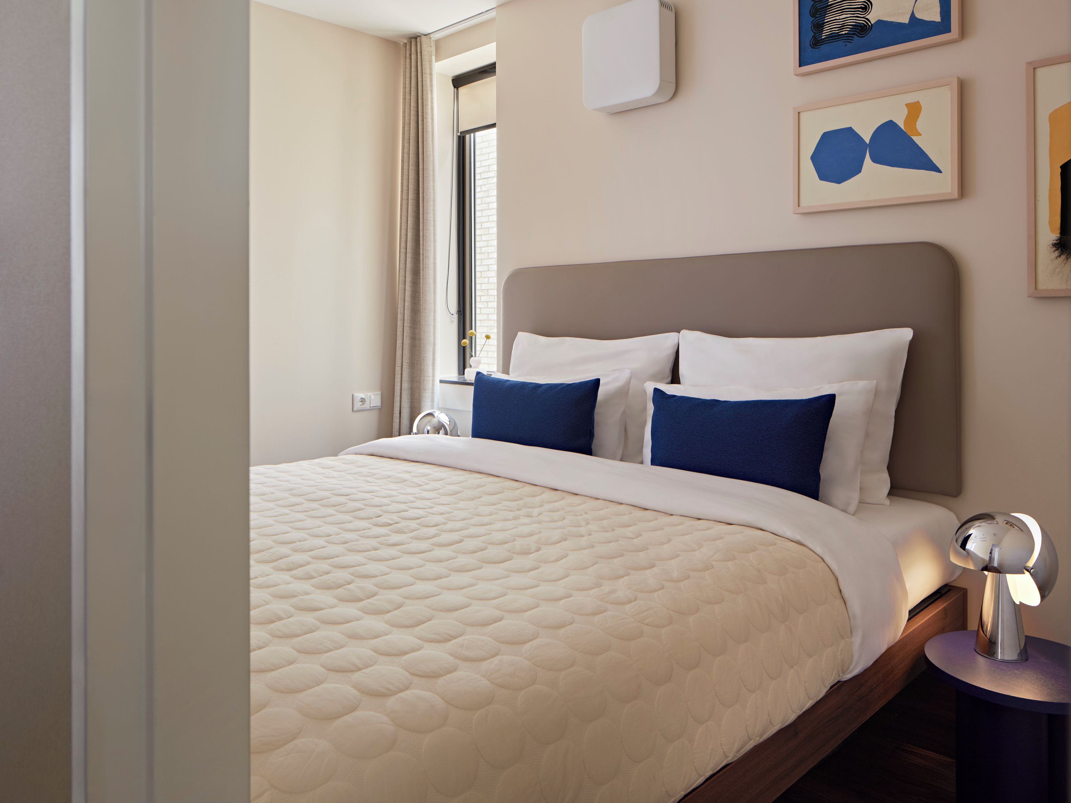 A hotel room with a bed, bedside tables, and a window with curtains.