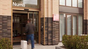 A building entrance with a sign reading 'Numa' and a smaller sign indicating 'The Hague Scheveningen.'