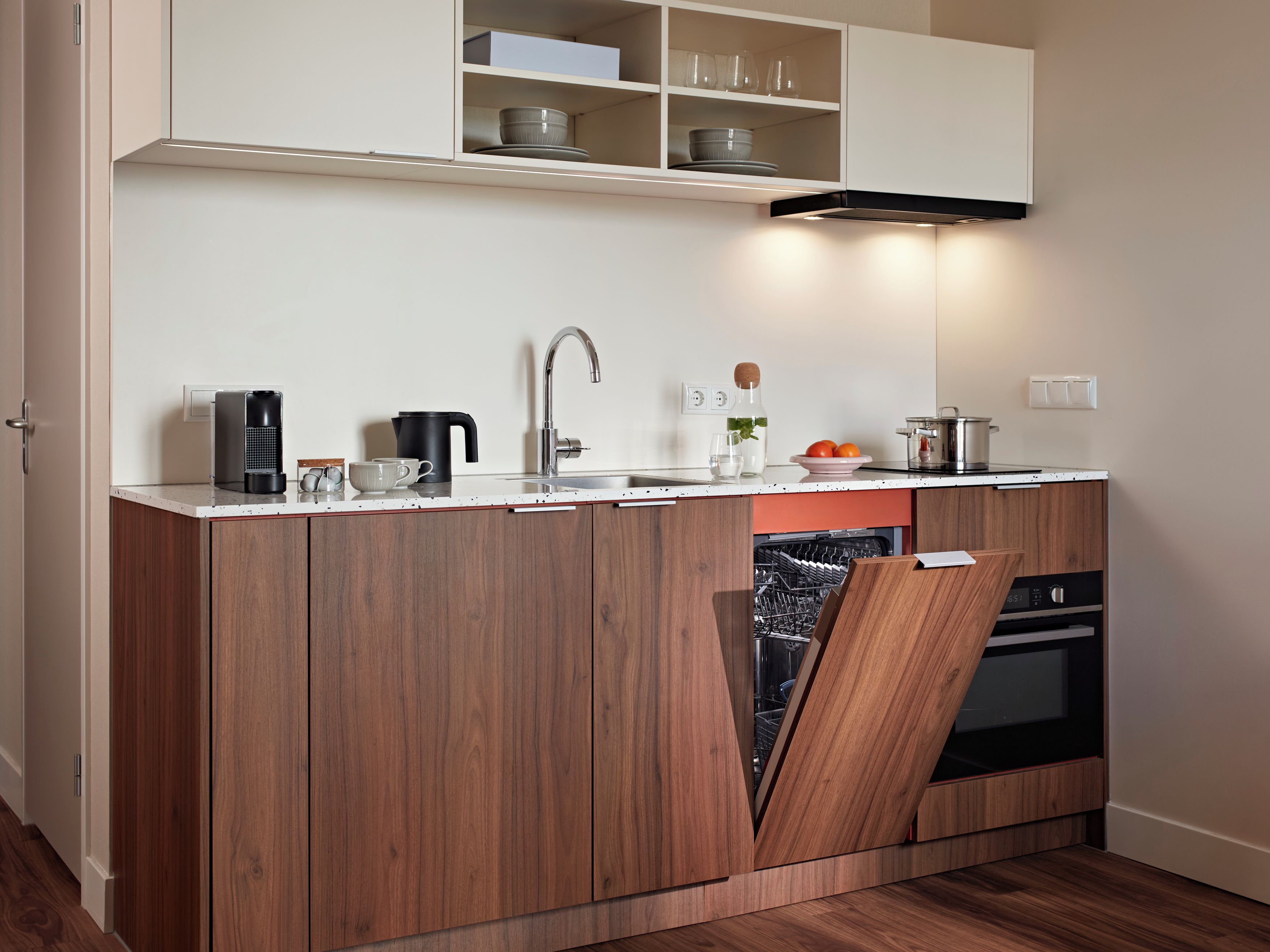 Een moderne keuken met een ingebouwde vaatwasser, een koffieapparaat en een waterkoker.