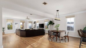 A spacious living area with a large L-shaped sectional sofa, a dining table with chairs, and a flat-screen TV mounted on the wall. - The Lamar Lookout + 3BR + Skyline Views in Austin (Austin)