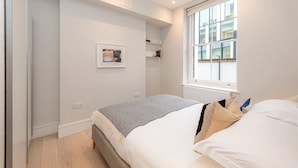A bedroom with a bed, a window, a framed picture on the wall, and a radiator. - Apartment-sleeps4-parking-100walkingscore (London)