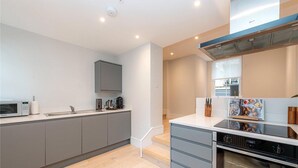 A modern kitchen with grey cabinets, a built-in oven, and a microwave. - Apartment-sleeps4-parking-100walkingscore (London)
