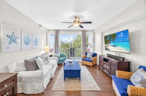 A living room with a white sofa, blue armchair, and a flat-screen TV on a stand.
