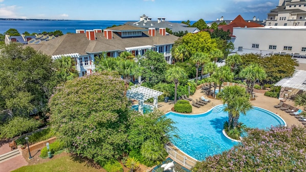 A resort with a swimming pool surrounded by lush greenery and a view of the ocean.