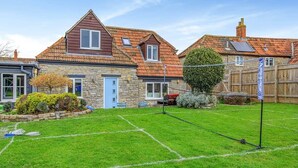 Il s’agit d’une propriété résidentielle dotée d’une pelouse bien entretenue, d’une maison en pierre avec un toit en tuiles et d’un petit jardin.