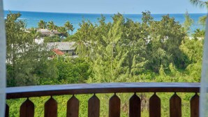 A view from a balcony overlooking a beach with palm trees and a clear blue sky. - Sandy Toes, 2br Apt at the beachfront, Diani (Diani Beach)
