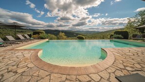 A clear blue pool with a stone deck, surrounded by lounge chairs and a scenic mountain view. - Borgo Le Noci Chianti Retreat & Pool (Gaiole in Chianti)