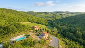 A villa with a swimming pool, surrounded by lush greenery and vineyards. - Borgo Le Noci Chianti Retreat & Pool (Gaiole in Chianti)