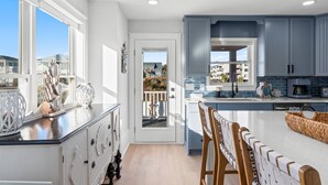 Cozinha moderna com uma ilha grande, armários brancos e vista para o exterior.