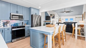 Uma cozinha moderna com armários azuis, eletrodomésticos de aço inoxidável e uma ilha central com banquetas.